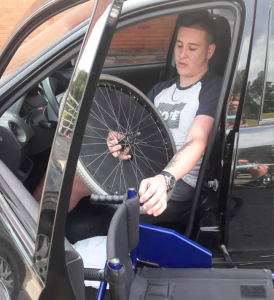 Participante do Programa de Habilidades em Cadeira de Rodas retirando sua cadeira de rodas de dentro do carro.